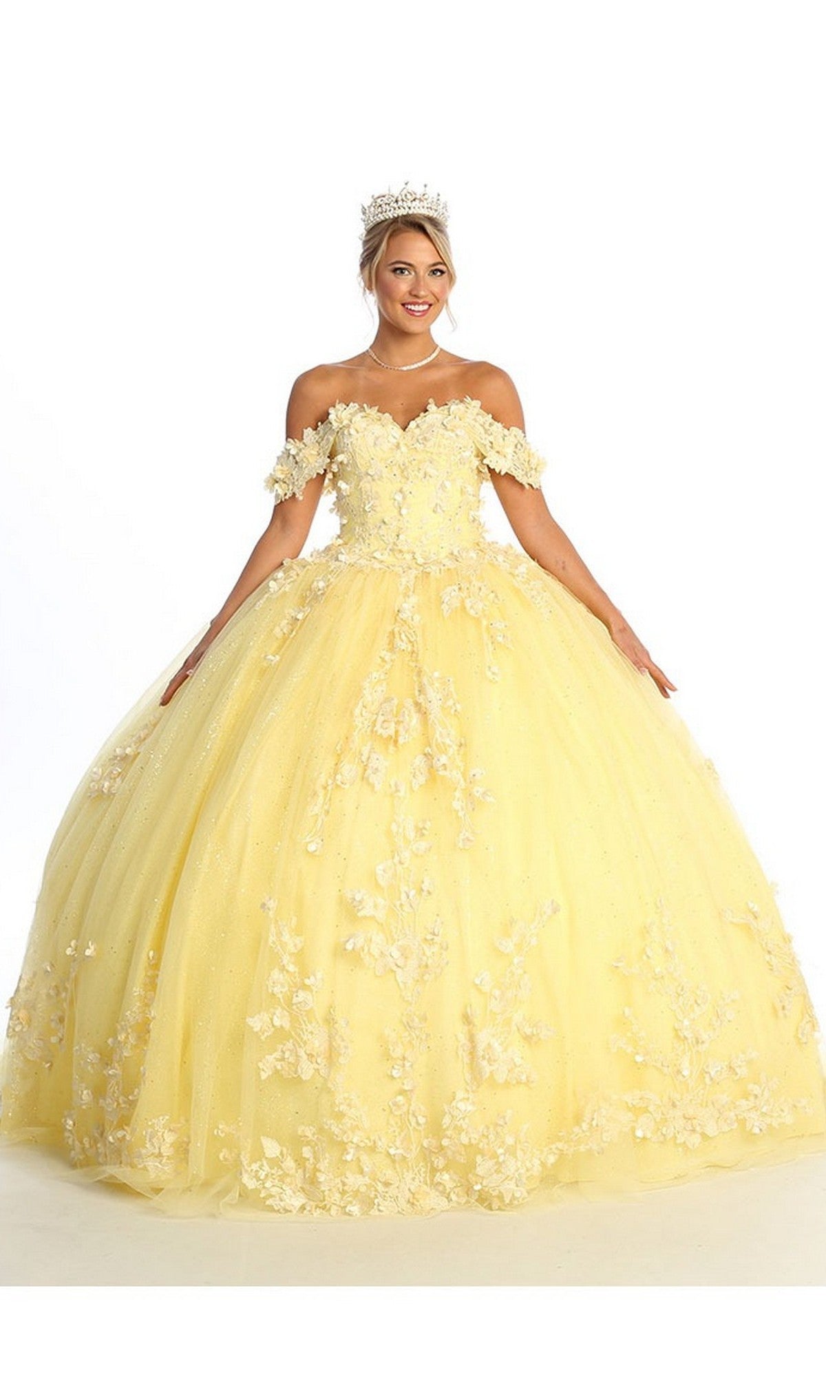 A woman wearing the Quinceanera Dress CHF3074 By Chicas in yellow, an off-the-shoulder ball gown adorned with floral details and delicate lace embroidery, paired with a tiara, stands against a white background.